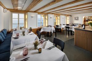 a restaurant with white tables and chairs and windows at La Colombe Boutique Hotel in Zug