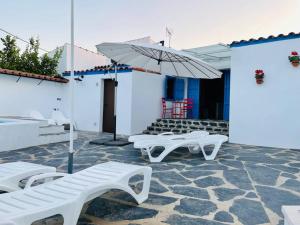eine Terrasse mit zwei weißen Bänken und einem Sonnenschirm in der Unterkunft BORBOLETA AZUL ALOJAMIENTO TURISTICO in Villarreal