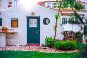 a white house with a blue door at Casa Paço D`Ilhas in Ericeira