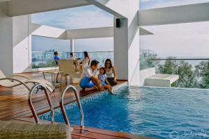 Un grupo de personas sentadas alrededor de una piscina. en Sunrise Gurney Executive Premium Suite, en George Town