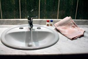 a white bathroom sink with a faucet and two bottles at Hostal Patrimonio - Sucre in Sucre