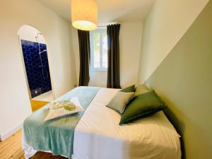 - une petite chambre avec un lit et des oreillers verts dans l'établissement Gite des Platanes, 