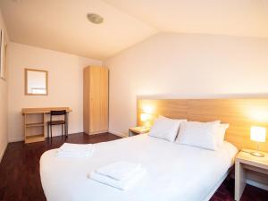a hotel room with a bed, chair, and nightstand at Residhotel St Etienne Centre in Saint-Étienne
