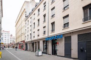 un bâtiment avec un panneau sur le côté d'une rue dans l'établissement Residhotel St Etienne Centre, à Saint-Étienne