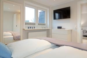 a white bedroom with a bed and a tv at Ferienwohnung Ben mit exklusiver Dachterrasse in Tinnum