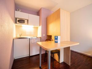 a small kitchen with a table and a refrigerator at Residhotel St Etienne Centre in Saint-Étienne