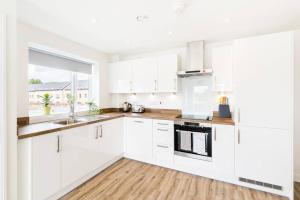 a white kitchen with white cabinets and a window at SUNLIGHT CITY CENTRE Flat WITH FREE PARKING in Birmingham