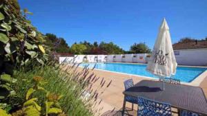 a table with an umbrella next to a swimming pool at New Forest Retreat Shorefield Country Park in Lymington