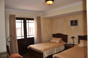 a bedroom with two beds and a window at Hostal Patrimonio - Sucre in Sucre