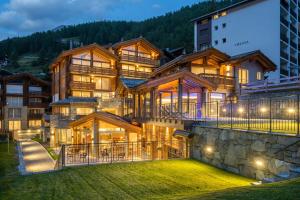 une grande maison avec une montagne dans l'établissement Luxury Residence Colosseo Zermatt, à Zermatt