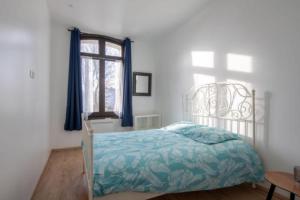 - une chambre avec un lit et une fenêtre avec des rideaux bleus dans l'établissement L'escapade Dieppoise - 3 chambres, 1er étage, à Dieppe