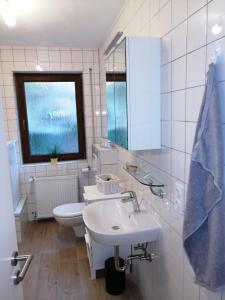 a white bathroom with a sink and a toilet at Ebenerdige Ferienwohnung mit großer Terrasse in der Nähe des Waldes, zum wohlfühlen in Schoneck