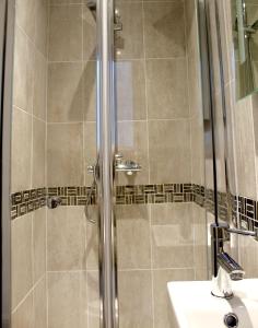 una ducha con una puerta de cristal junto a un lavabo en The Duffryn, en Mountain Ash