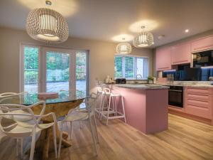 een keuken met roze kasten en een glazen tafel en stoelen bij The Neon Rose in Bowness-on-Windermere