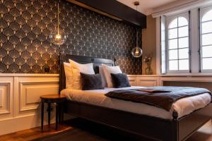 een slaapkamer met een bed met een zwarte muur bij Hotel Ô Château in Hayange