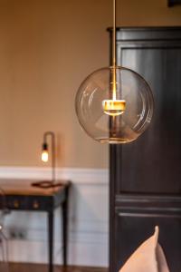 een glaslamp die boven een tafel hangt bij Hotel Ô Château in Hayange