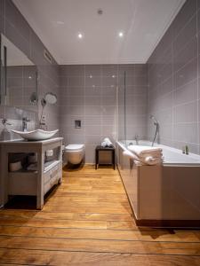 een badkamer met 2 wastafels, een bad en een toilet bij Hotel Ô Château in Hayange
