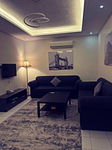 uma sala de estar com um sofá, uma mesa e uma televisão em ايزي للوحدات المخدومة em Abḩur al Janūbīyah