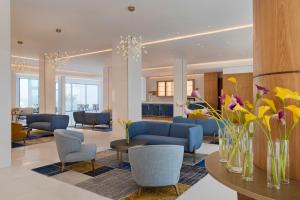 a lobby with couches and chairs and flowers on a table at Herbert Samuel Hod Dead Sea Hotel in Ein Bokek