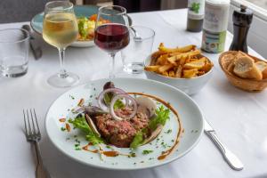 a table with a plate of food and glasses of wine at Hotel Le Rayon Vert in Étretat