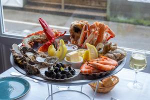 a plate of seafood on a table with a glass of wine at Hotel Le Rayon Vert in Étretat