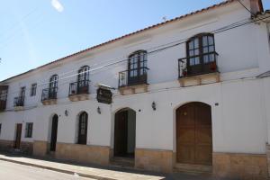 a white building with brown doors and windows at Hostal Patrimonio - Sucre in Sucre
