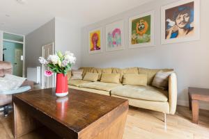 sala de estar con sofá y mesa con flores. en Second Nest Hampton Street, en Londres