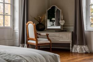 Hotel Ô Château في Hayange: غرفة نوم مع كرسي وخزانة مع مرآة