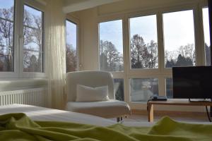 Schlafzimmer mit einem Stuhl, einem Schreibtisch und Fenstern in der Unterkunft Hotel Lindenallee in Lindau