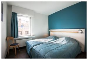 a bedroom with a bed and a blue wall at Vayamundo Oostende - Apartments in Ostend