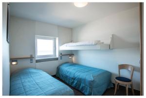 a bedroom with two beds and a chair and a window at Vayamundo Oostende - Apartments in Ostend