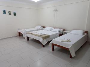 een kamer met 2 bedden en een tafel en stoelen bij Riachuelo Hotel in Resende