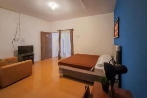 - une chambre avec un lit, une télévision et un canapé dans l'établissement Syafa Homestay Syariah Mitra RedDoorz, à Jembel