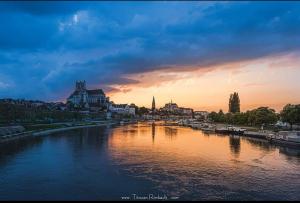 a view of a river with a city at sunset at La Maison des Artistes in Auxerre