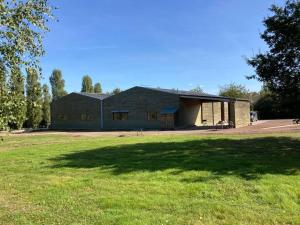 a large building with a grass field in front of it at Habitation en bois authentique in Venizy