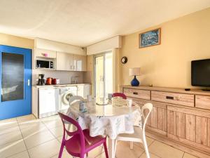 eine Küche mit einem Tisch und Stühlen sowie einem TV in der Unterkunft Apartment Le Capitole-2 by Interhome in Fréjus