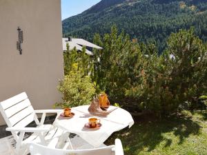 uma mesa e cadeiras brancas com vista para uma montanha em Apartment Residenz Surlej 6 by Interhome em St. Moritz