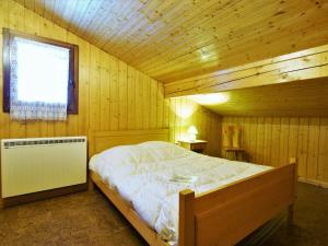 um quarto com uma cama num quarto de madeira em Chalet Pierre Blanche by Interhome em Servoz