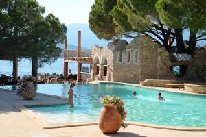 a group of people swimming in a swimming pool at Hôtel Le Belvédère in Porto-Vecchio