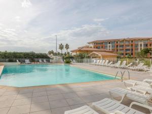 a swimming pool with lounge chairs and a hotel at Apartment Cap Hermes-2 by Interhome in Fréjus