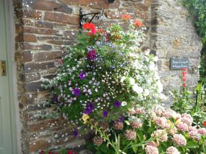 
a garden filled with flowers next to a brick wall at Rowan Retreat in Lanreath
