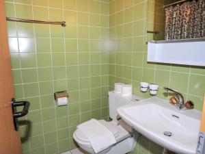 uma casa de banho com azulejos verdes, um WC e um lavatório. em Studio Krokus by Interhome em Wengen