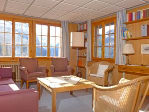 a living room with a table and chairs and windows at Apartment Drei Tannen by Interhome in Wengen
