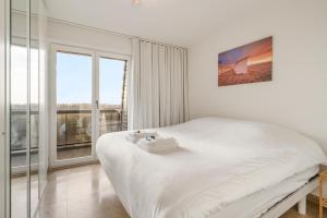 una camera bianca con un grande letto e finestre di Ster Der Zee-Fijn app met uitgestrekt zicht op zee a Koksijde