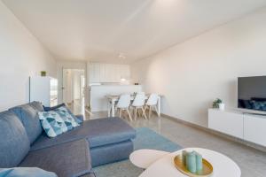 un soggiorno con divano blu e una cucina di Ster Der Zee-Fijn app met uitgestrekt zicht op zee a Koksijde