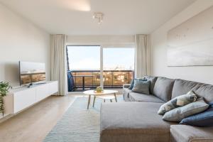 uma sala de estar com um sofá e uma televisão em Ster Der Zee-Fijn app met uitgestrekt zicht op zee em Koksijde
