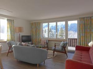 a living room with a couch and chairs and windows at Apartment Tschingelhorn by Interhome in Wengen