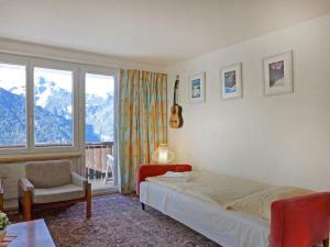 um quarto com uma cama, uma cadeira e uma janela em Apartment Tschingelhorn Apt- R by Interhome em Wengen