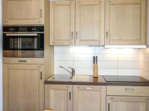 a kitchen with wooden cabinets and a sink at Apartment Le Clos de la Fontaine-1 by Interhome in Saint-Gervais-les-Bains