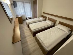 2 Betten in einem kleinen Zimmer mit Spiegel in der Unterkunft Hotel Le Baron in Timişoara